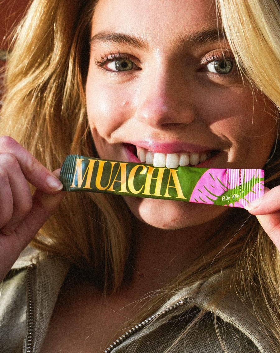 Model biting a Muacha stick pack